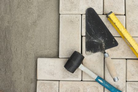 The master lays paving stones in layers. Garden brick pathway paving by professional paver worker.